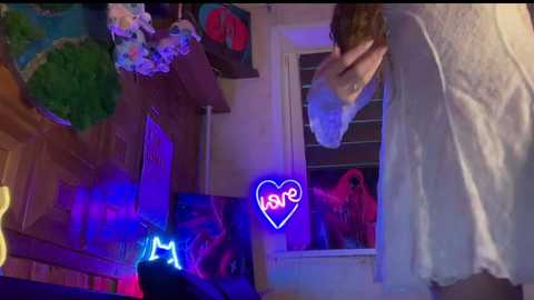 A video captures a dimly lit room with purple neon lights, a white-clothed person, and a pink toy car visible through a window.