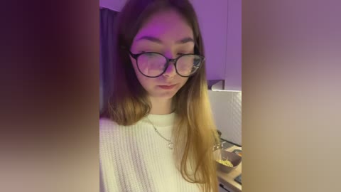 Video of a young Asian woman with long, straight, light brown hair, wearing black-framed glasses, a white knit sweater, and a silver necklace, standing indoors with a dim, purple-lit background.