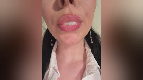 Video of a woman's lower face, focusing on her full lips and shiny, straight black hair. She's wearing a white shirt with a hint of cleavage. The background is blurred, highlighting her smooth, fair skin.