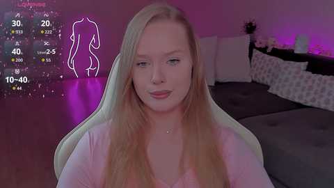 Video of a young, fair-skinned woman with long, straight blonde hair, sitting in a gaming chair, wearing a pink top, in a dimly-lit bedroom with purple ambient lighting.