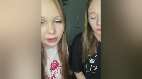 Video of two young girls with long, straight hair, one wearing a red graphic T-shirt, the other a black shirt with white text, standing close together indoors.