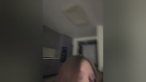 A blurry video of a man's face in a dimly lit room, with a television mounted on the wall in the background, creating a sense of mystery and tension.