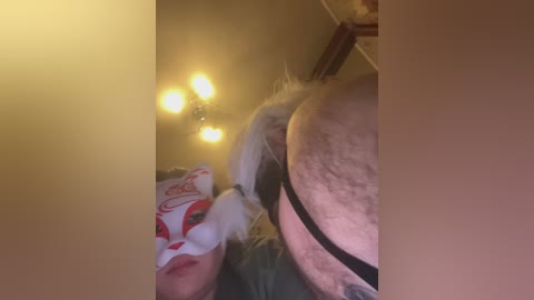 Video of a woman in a red and white fox mask, with her hands on her chest, in a dimly lit room with yellow light bulbs.