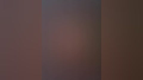 A video of a nude female torso with a small, indistinct head in the center, surrounded by a blurred, reddish-brown background. The skin appears smooth and unblemished, with no discernible facial features.