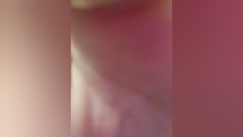 The image is a blurred, close-up video of a person's face, featuring soft, warm colors. The subject's features are indistinguishable due to the high level of blurriness, but the background has a gradient of pink and red hues.