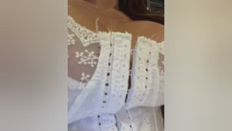 A close-up video of a woman's bare chest, adorned with a white lace bra featuring intricate floral patterns. The image is partially blurred, with the focus on the lingerie.