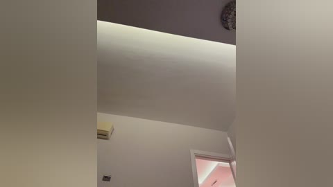 A video of a modern, minimalist room with white walls, a large ceiling light fixture, and an air conditioning unit. The room has a clean, uncluttered appearance.