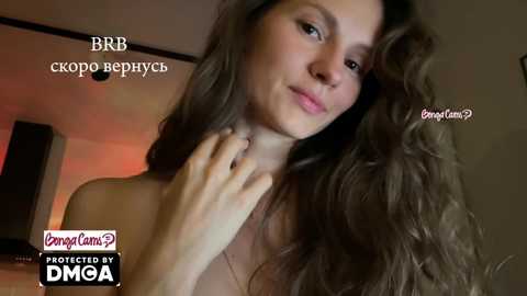 Video of a topless woman with long, wavy brown hair, fair skin, and a slender build. She gazes slightly to the side with a soft smile. Text reads \"BBB,\" \"skrobo Berezhno,\" \"\u0411\u0411\u0411,\" \"\u0411\u0411\u0411,\" \"\u0414\u041c\u0413\u0410,\" and \"\u0411\u0411\u0411.\