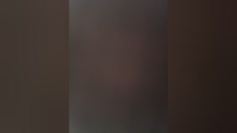 Video of a blurred, indistinct person standing against a dark background, creating a mysterious, somewhat eerie atmosphere. The figure's silhouette and clothing are barely discernible.