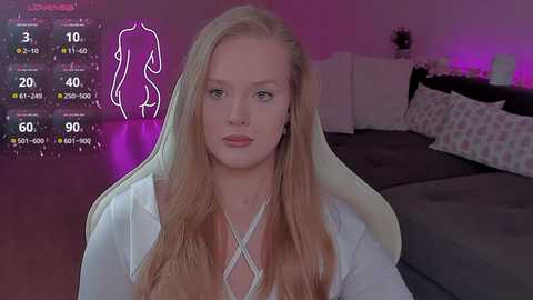 Video of a fair-skinned, blonde woman with long hair, wearing a white top, sitting on a dark bed with white pillows and a pink nightstand. Digital fitness tracking overlay on left.