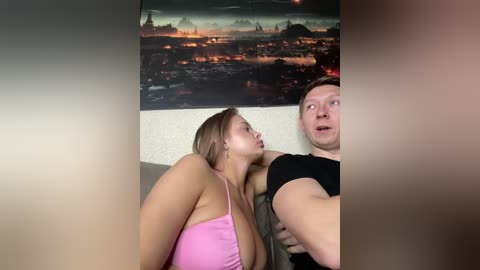 Video of a shocked man with a shocked woman in a pink tank top, both indoors against a cityscape backdrop.