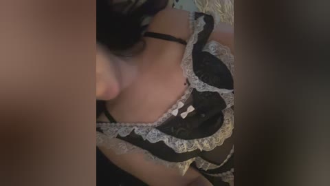 Video of a woman in a black lace lingerie set with white trim, lying on her back, with blurred edges and soft lighting.