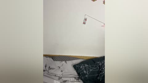 A video showing a hospital room with a white wall, a medical drip stand, and a bed with grey and white patterned bedding, giving a sterile, clinical feel.