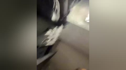 A blurry, grainy video of a partially obscured woman lying on a dark, possibly wooden floor. Her face is visible, showing dark hair and a serene expression. The lighting is dim, creating a moody, somewhat mysterious atmosphere.