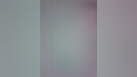 A video of a minimalist abstract composition featuring soft pastel colors. The image is composed of two intersecting vertical planes, one in light gray and the other in light pink, creating a gradient effect. The background is smooth and seamless, lacking any visible texture or objects.