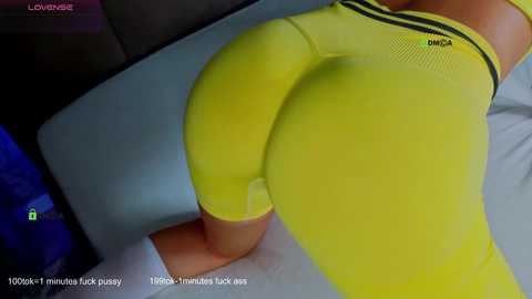Video of a woman's buttocks in tight yellow leggings, captured from a first-person perspective. The image includes a timestamp, \"12:06 PM,\" and a text overlay reading, \"I'm feeling so sexy, fuck me baby!\