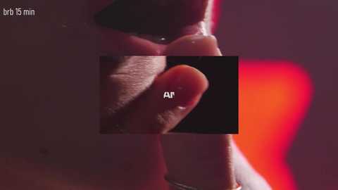 Video of a close-up of a person's lips and index finger, with a black box overlaying the finger. Text \"AI\" is written above the box. Background is blurred, with a red and purple gradient.