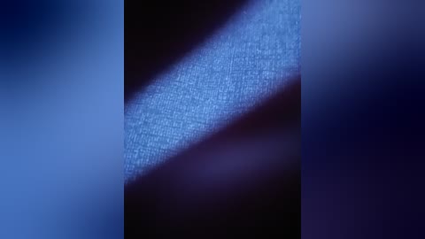 Video of a close-up, textured, blue fabric with a diagonal crease, set against a dark background, creating a dynamic visual effect.