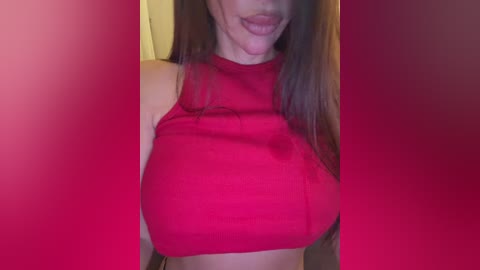 A video of a woman with long brown hair, wearing a red sleeveless crop top, smiling with her tongue out.