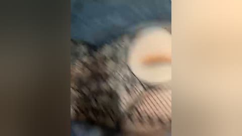 A blurry video featuring a partially visible person with light skin, wearing a grey hoodie, standing in front of a blue background.