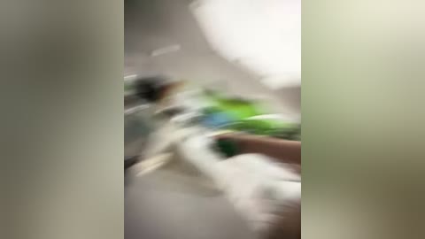 Blurry video of a white cat with green eyes, possibly in motion, against a background of green and white walls, with a hand visible on the right.