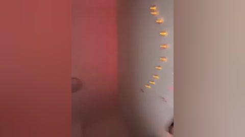 A video of a blurred, red-walled room with a white, cylindrical object, partially obscured, featuring small yellow lights and a label. The image has a soft focus, emphasizing a cozy, intimate atmosphere.