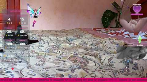 Video of a woman lying on a bed with a colorful, patterned duvet, a cat nearby. Digital overlays show game elements, including a butterfly and a heart icon.