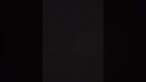 A video with a dark, nearly black background, featuring a vertical, narrow strip of light that runs down the center. The image is minimalistic and stark, with no discernible objects or details visible.
