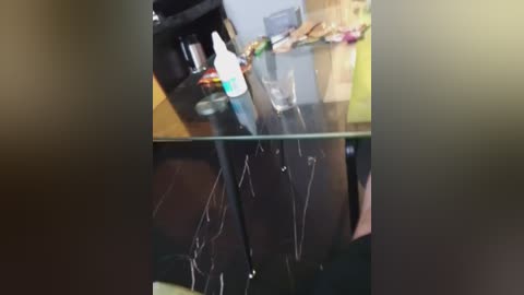 Video of a kitchen counter with a glass pane showing handwritten notes, a bottle of hand sanitizer, and a few scattered items on a wooden surface.
