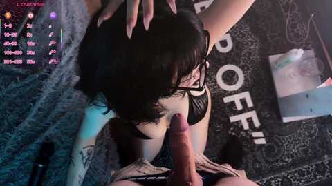 Video of a woman with long black hair and glasses performing oral sex on a man. Background includes a \"Starbucks\" sign and a dark patterned rug.