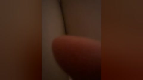 A blurry close-up video of a human hand with a slightly tanned complexion, fingers spread, and a prominent thumb in the center. The background is indistinct, featuring muted, warm colors.