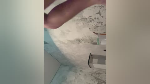 A close-up video of a person's hand holding a cylindrical object over a sink with peeling paint and mold on the walls. The sink is white, and the person's hand is pale.