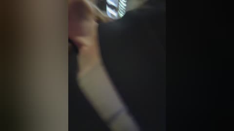 Blurred, low-resolution video of a woman with blonde hair in a dark, possibly indoor setting with a black backdrop.