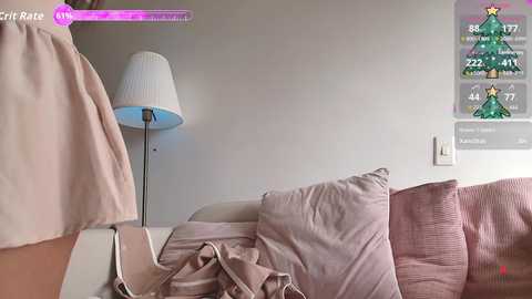 A video of a messy beige couch with a white lamp and a digital screen displaying game stats in a minimalist room.