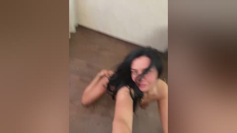 A blurry video shows a young woman with long black hair, lying on a brown carpeted floor in a dimly lit room.