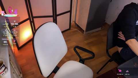 A video depicts a modern office with a white chair, wooden floor, and a person sitting in a black chair. The room has a warm light and a digital interface showing a virtual assistant.