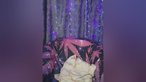 A video of a cozy, dimly lit room with a black and pink feather-patterned armchair. The chair is covered with a beige blanket, and the background features a sequined curtain with twinkling blue lights.