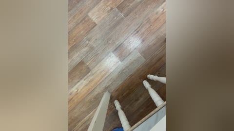 Video of a ceiling with wooden planks, showing the underside of a ladder with white legs. The background is a beige wall.