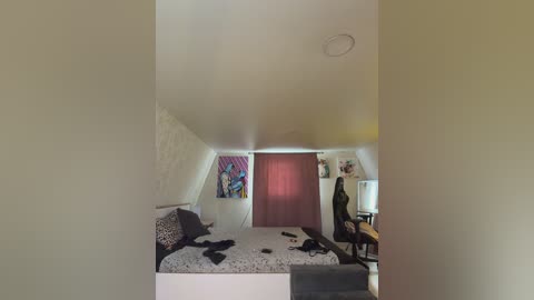 A video of a messy attic bedroom with a white bed, scattered clothes, a black chair, a red curtain, and colorful wall art.