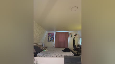 A video of a small, cozy bedroom with a sloped ceiling, featuring a bed with a white quilt, a desk with a computer, and colorful artwork on the walls.