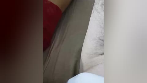 Video of a close-up of a red bra strap and a beige arm, suggesting a woman's intimate moment, with a focus on texture and color contrast.