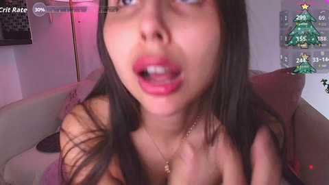 A video shows a young woman with long dark hair, wearing a necklace, and open-mouthed expression, possibly in a video game.