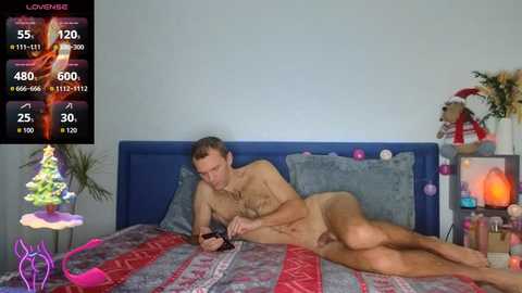 A video of a naked man lying on a bed, reading a book, in a cozy room with Christmas decorations.