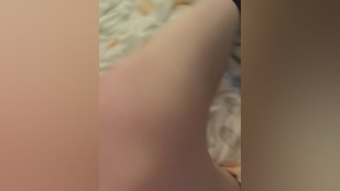 Video of a pale, nude person, likely female, lying on a bed with floral-patterned sheets. The focus is on their buttocks and thighs, with a soft, blurred background.