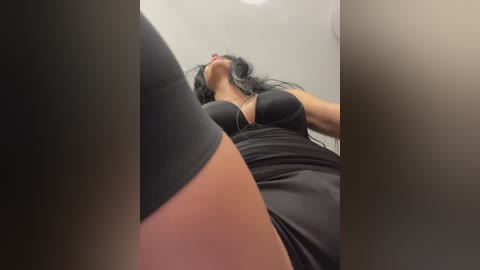 Video of a woman in a black dress, viewed from below, with a blurred background and slightly out-of-focus foreground.