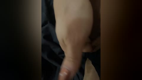 A close-up video shows a nude person with fair skin, their arm reaching out, partially covered by a dark fabric. The image is blurred, focusing on the arm and hand.