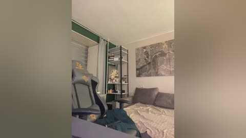 A video of a modern, minimalist bedroom with a blue gaming chair, green shelves, and gray bedding. The walls feature a black and white abstract art piece.