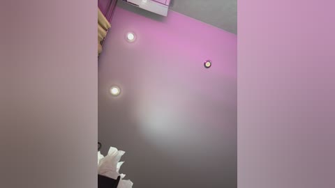 Video of a room with a pinkish-purple ceiling, featuring three recessed lights and a small circular light fixture, with white tissue boxes visible at the bottom.