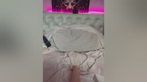 A video shows a white, tufted headboard with a pink light strip, a plush white pillow, and a black vibrator on a messy bed.