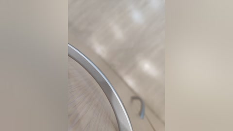 Video of a close-up of a sleek, silver handle of a kitchen appliance, with a blurred beige background suggesting a kitchen setting. The image focuses on the metallic texture and smooth, curved design of the handle.